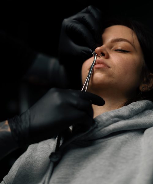 Piercing process Professional nose piercing of girl in disposable black gloves sexy nose ring