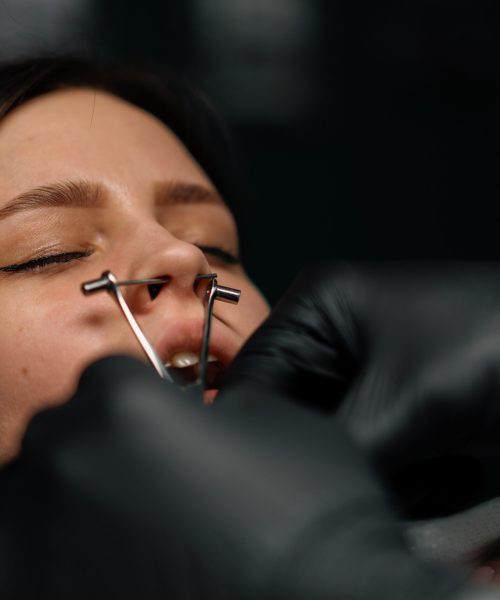 Piercing studio. a master pierces a girl's nose
