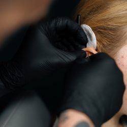 Piercing studio master pierces a girl's ear with needle Piercing concept