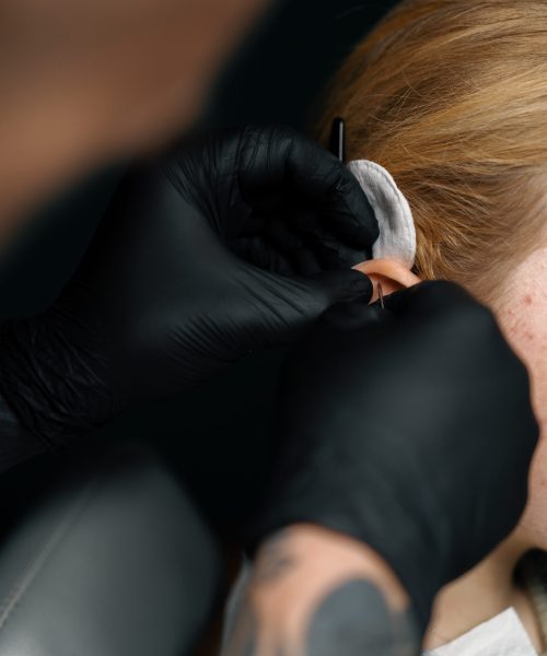 Piercing studio master pierces a girl's ear with needle Piercing concept