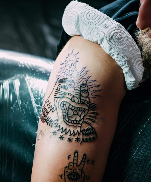 partial view of man with new tattoo on shoulder at tattoo salon