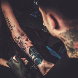 Professional tattoo artist makes a tattoo on a young girl's hand.