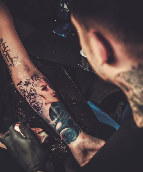 Professional tattoo artist makes a tattoo on a young girl's hand.